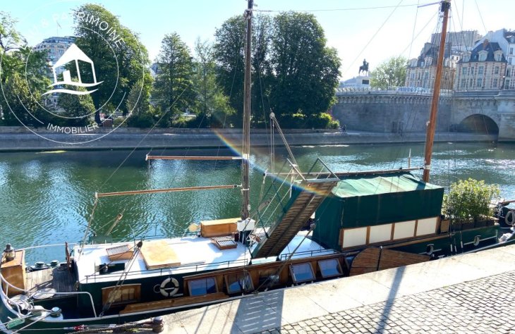 Péniche habitable de type Tjalk avec ses béquilles à quai le long de la seine.