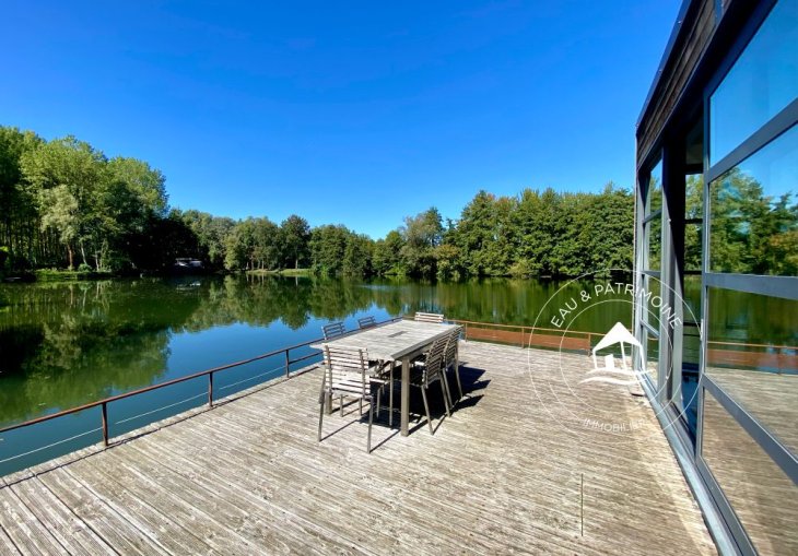 Maison flottante à vendre et sa terrasse offrant espace et liberté sur l'eau dans un cadre naturel.